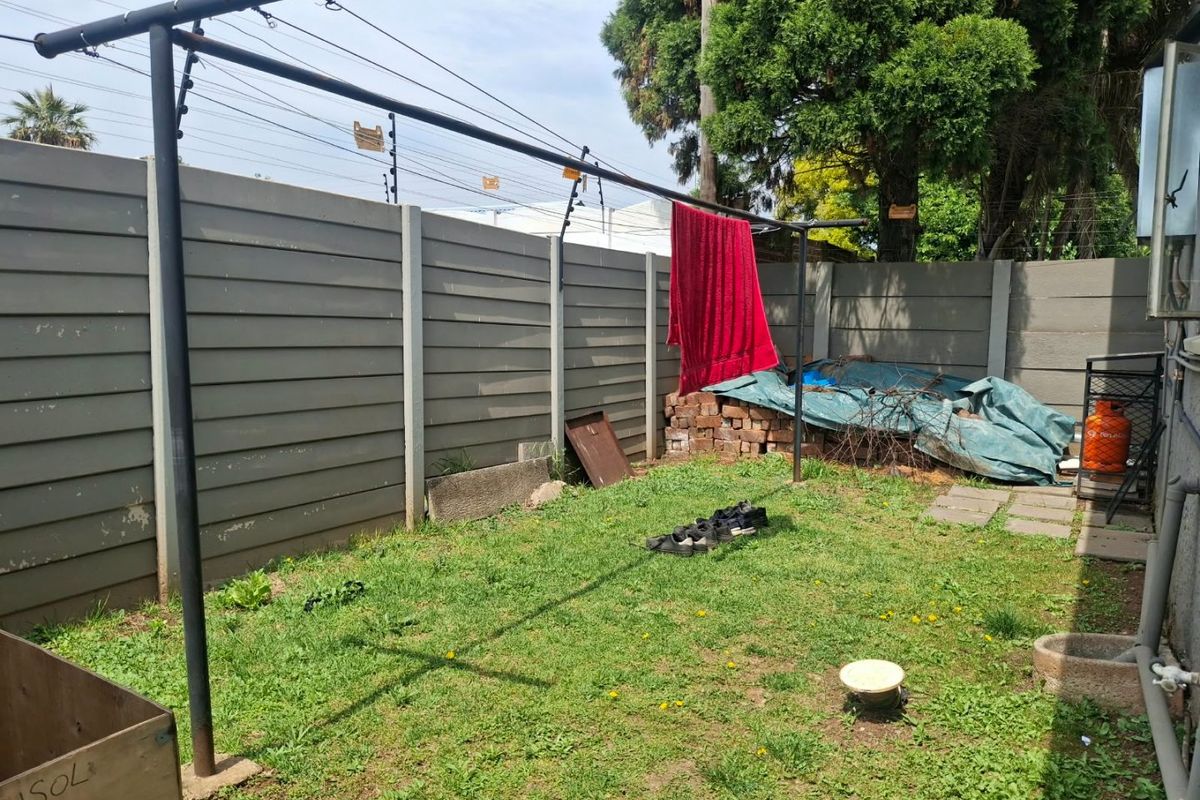 A rear garden area featuring a precast concrete boundary wall with electric fencing and a metal washing line structure.