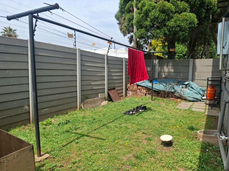 A rear garden area featuring a precast concrete boundary wall with electric fencing and a metal washing line structure.