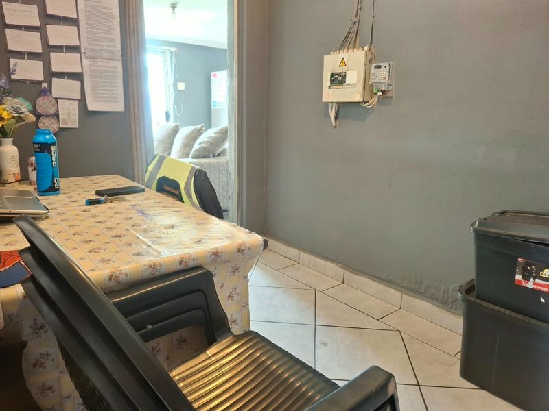 A utility area featuring tiled flooring and a wall-mounted electrical distribution board, providing functional space for storage or home management.