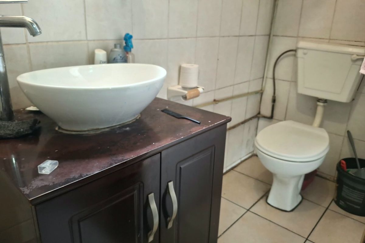 A functional bathroom featuring a vessel sink on a vanity cabinet, a standard toilet, and tiled walls and flooring.