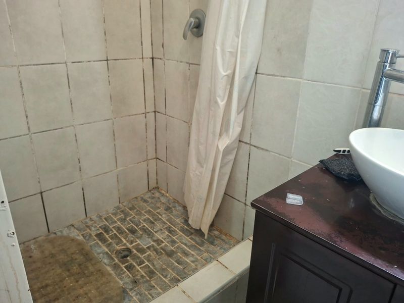 Bathroom featuring a tiled shower enclosure with a shower mixer and a vessel sink mounted on a vanity cabinet.
