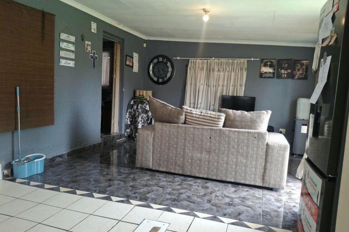 A living room area featuring dark grey walls and contrasting tiled flooring, providing a functional space for relaxation.