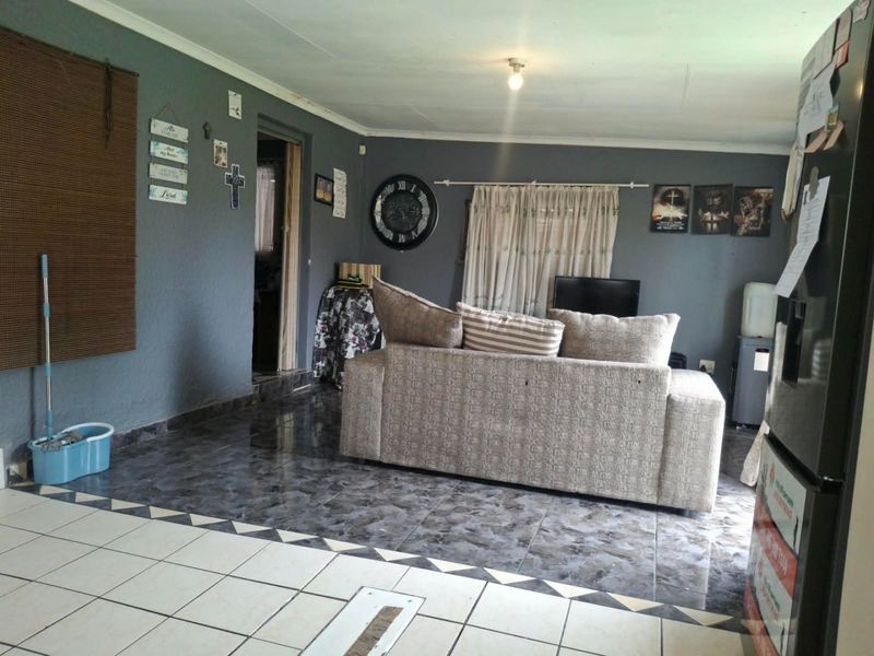 A living room area featuring dark grey walls and contrasting tiled flooring, providing a functional space for relaxation.