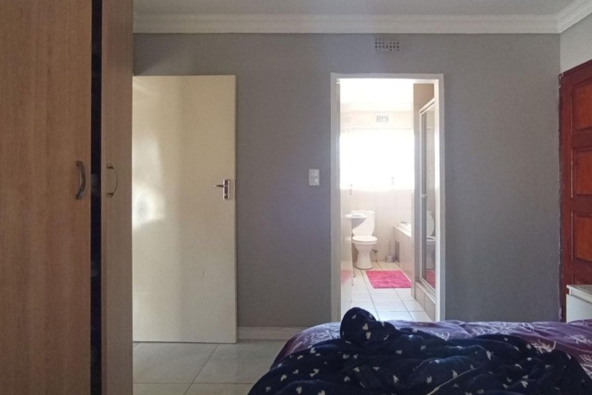 Bedroom featuring built-in cupboards and direct access to an en-suite bathroom with neutral wall finishes.