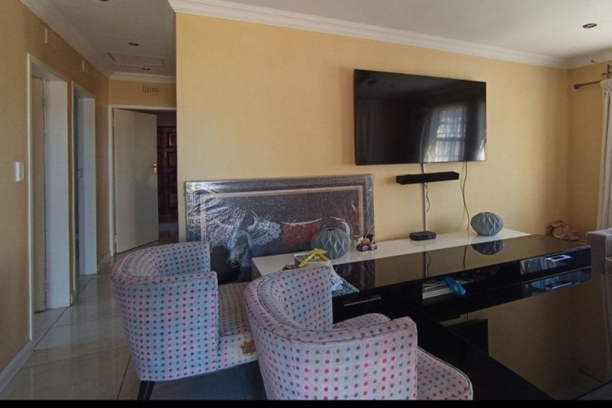 A living room featuring tiled flooring, coved ceilings, and recessed downlighting, providing a functional space for relaxation and entertainment.