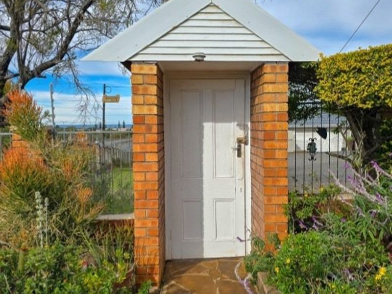 A charming brick-pillared entrance gate with a gabled roof and stone pathway, providing a classic and welcoming access point to the property.