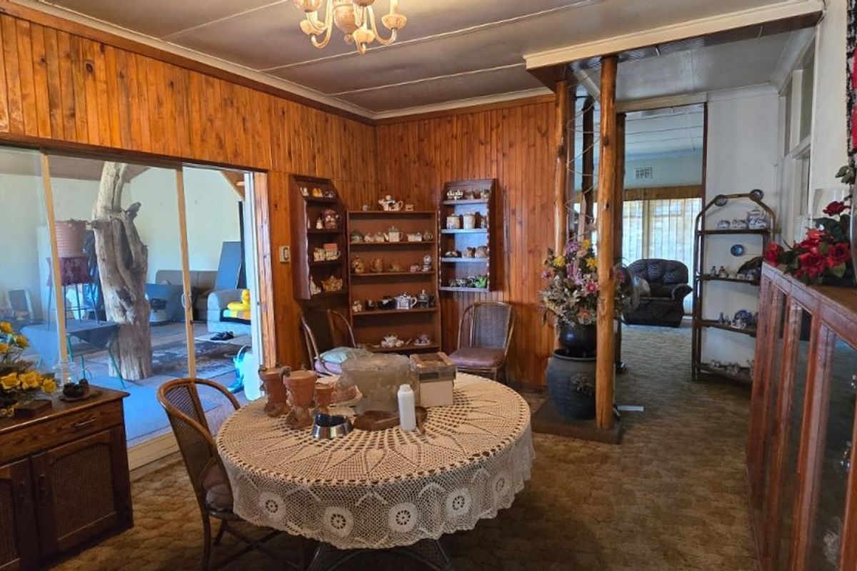 Living room featuring wood paneling, built-in shelving, and sliding glass doors leading to an outdoor area, with dated finishes throughout.