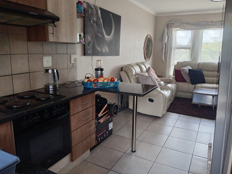 Open-plan living area featuring a compact kitchen with built-in oven, hob, extractor fan, and granite countertops, seamlessly flowing into the adjacent lounge space.