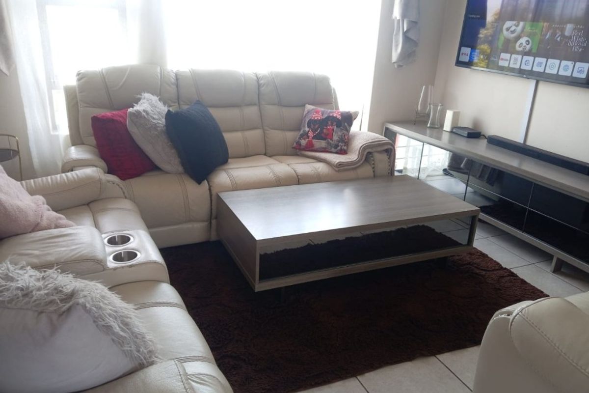 A comfortable living room area featuring tiled flooring and a wall-mounted television setup.