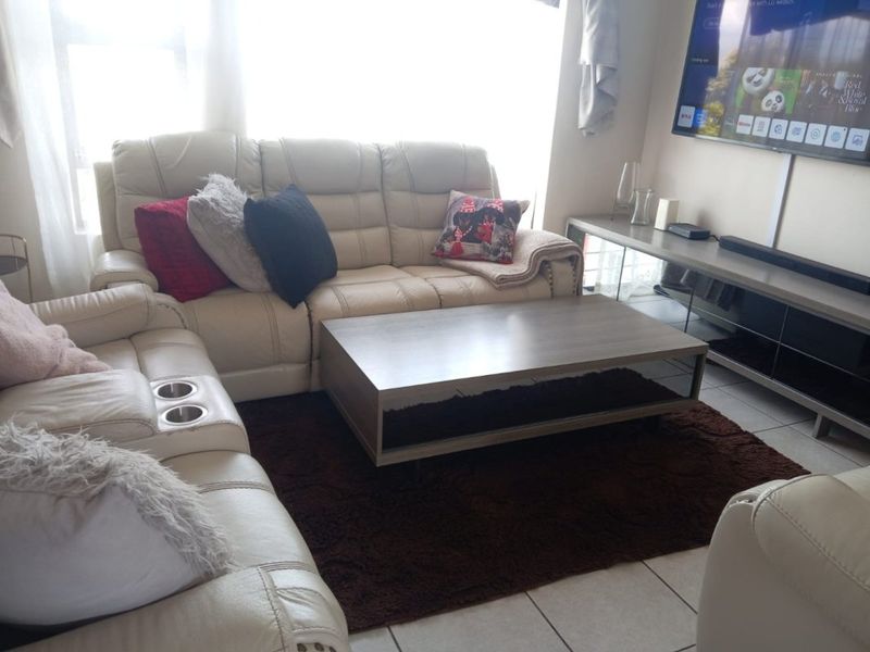 A comfortable living room area featuring tiled flooring and a wall-mounted television setup.