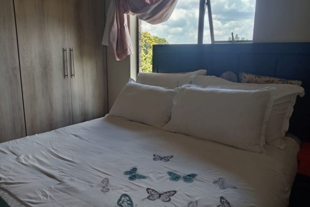 A bedroom featuring built-in wooden cupboards and a top-hung window providing natural light.
