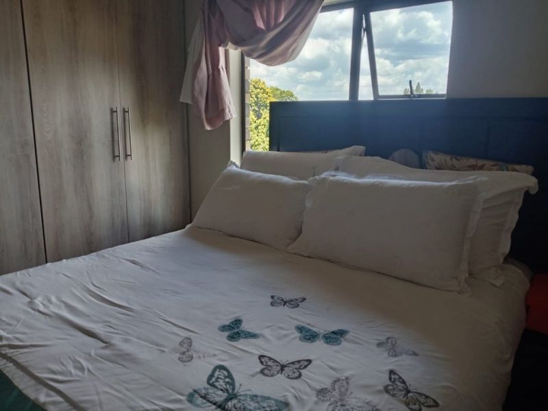 A bedroom featuring built-in wooden cupboards and a top-hung window providing natural light.