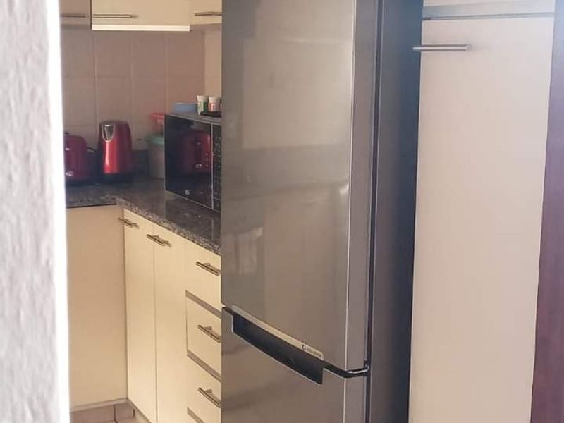 A compact kitchen featuring built-in cabinetry, granite countertops, and tiled flooring, providing a functional workspace within the apartment.