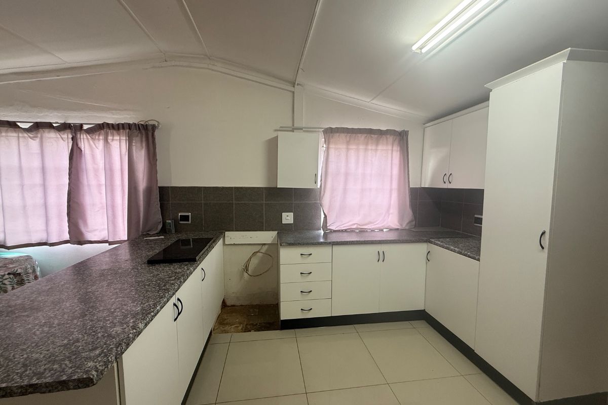 A functional kitchen featuring white cabinetry, granite-look laminate countertops, tiled backsplash, and tiled flooring, with a dedicated space for an under-counter appliance.