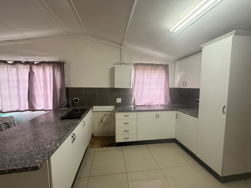 A functional kitchen featuring white cabinetry, granite-look laminate countertops, tiled backsplash, and tiled flooring, with a dedicated space for an under-counter appliance.