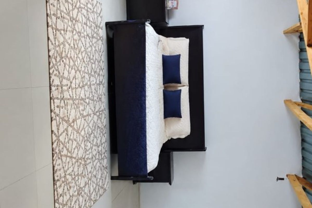 A bedroom featuring tiled flooring and exposed timber rafters, offering a functional space with potential for aesthetic enhancement.