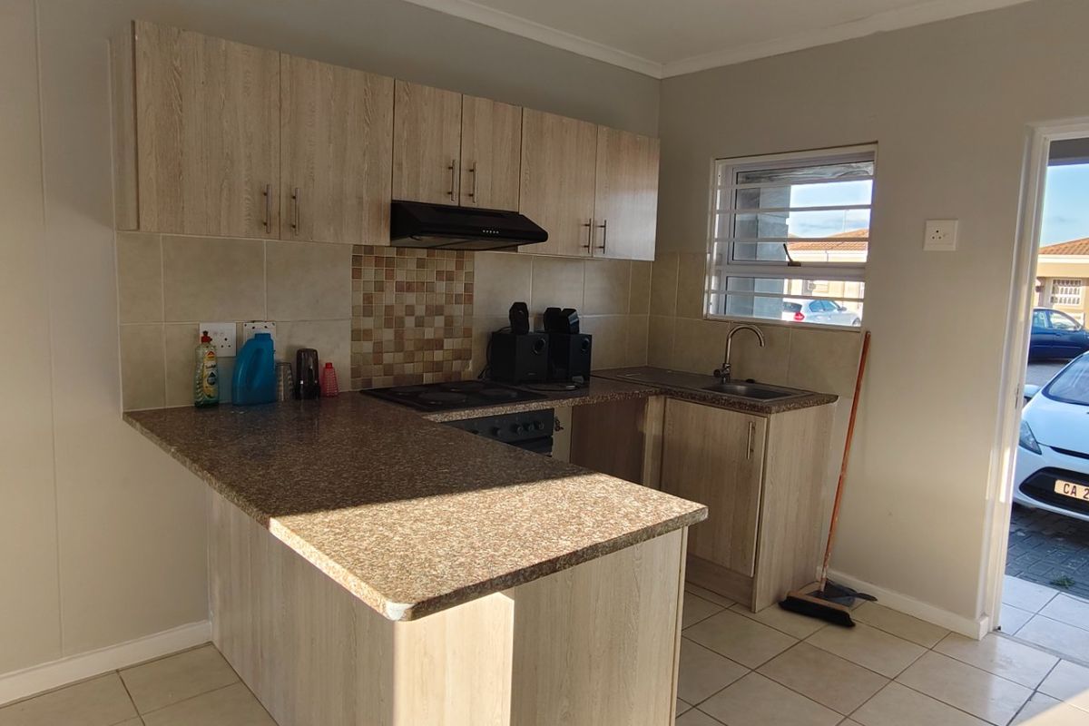 A functional kitchen featuring light wood-look cabinetry, granite-style countertops, a built-in oven with extractor fan, and direct access to the exterior.