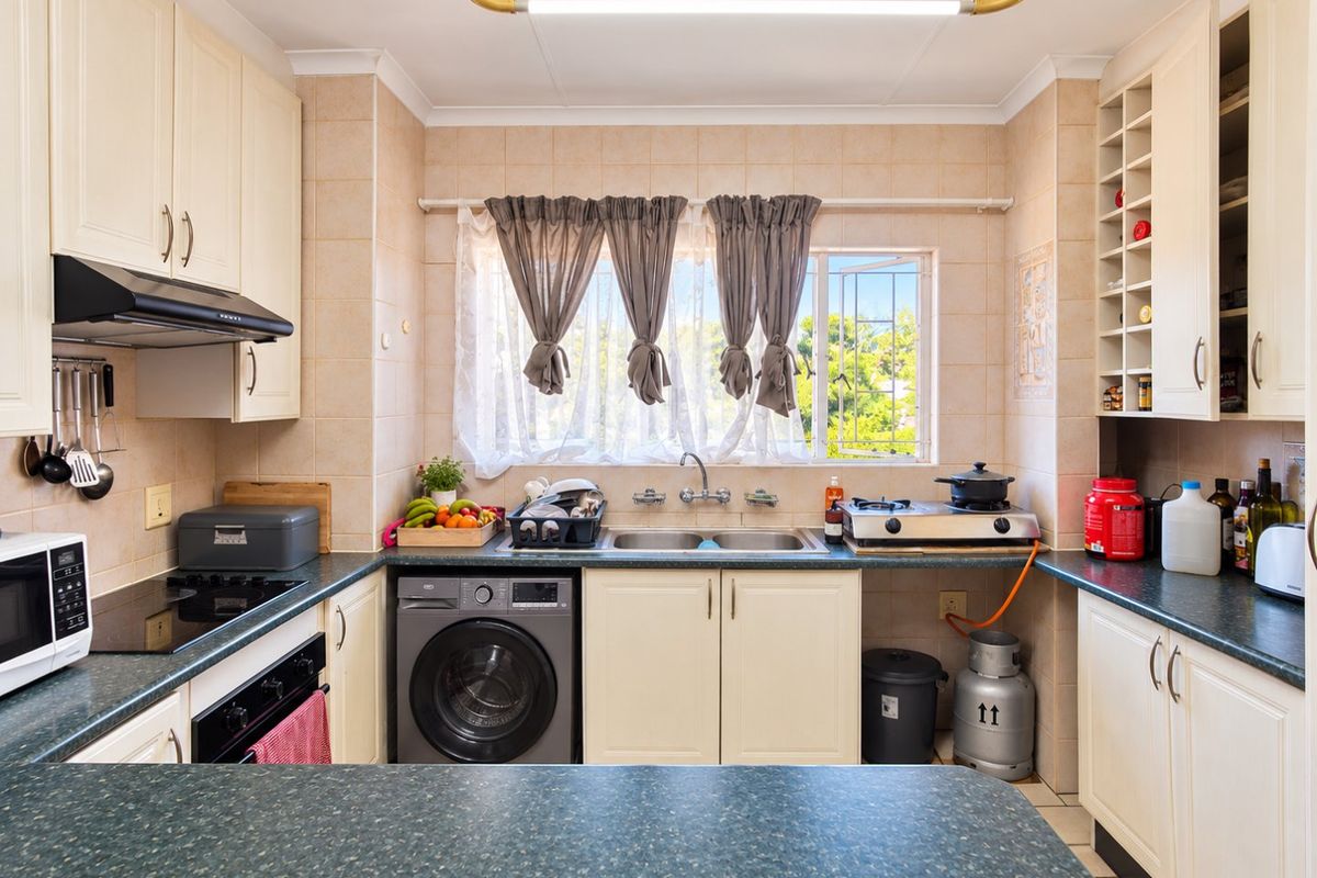 A functional kitchen featuring ample built-in cabinetry, laminate countertops, a double basin sink, and integrated cooking appliances with tiled splashbacks.