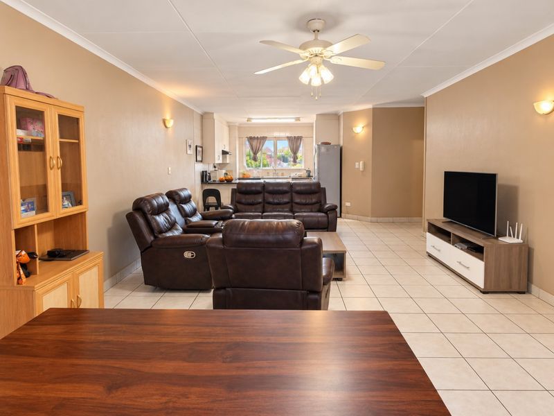 Spacious open-plan living and kitchen area featuring tiled flooring, ceiling fan, and neutral wall finishes, providing a functional and versatile layout.