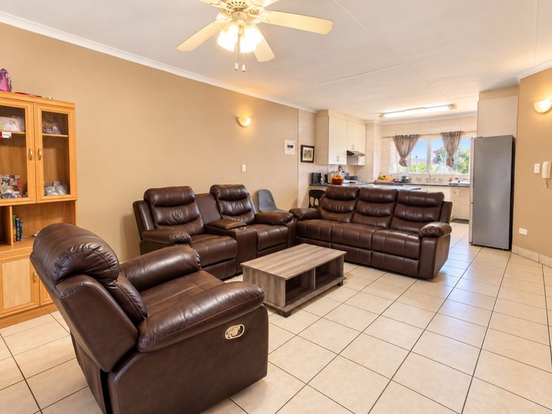 Open plan living area featuring tiled flooring, a ceiling fan, and an integrated kitchen with cabinetry and sink.