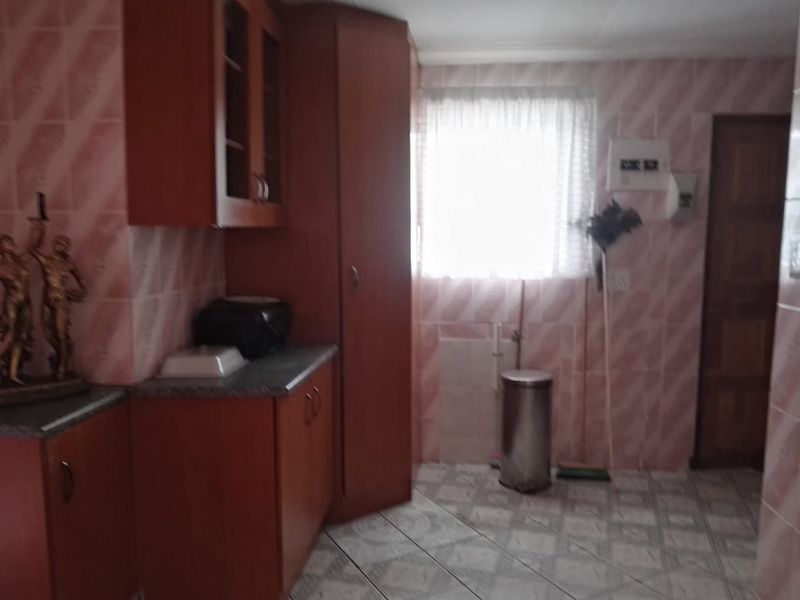 A dated kitchen featuring wooden cabinetry, tiled walls, and tiled flooring, requiring modernization to improve aesthetic appeal and functionality.