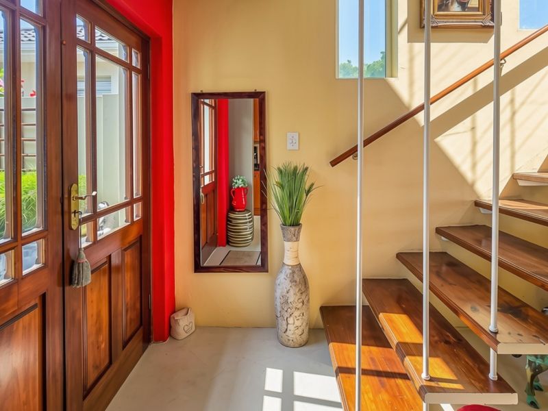 Welcoming entrance hall featuring a timber staircase with metal balustrades and a solid timber front door, leading into the main living area.