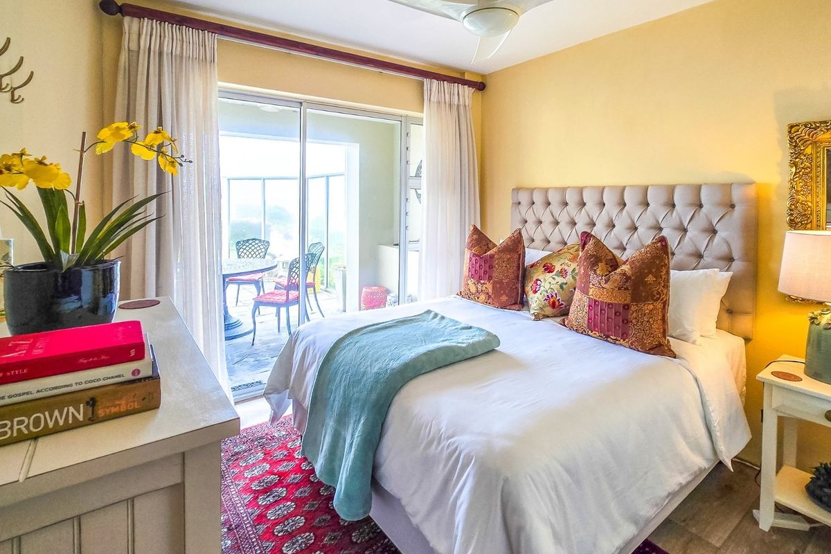A well-lit bedroom featuring a sliding glass door that opens onto a private balcony, providing natural light and outdoor access.
