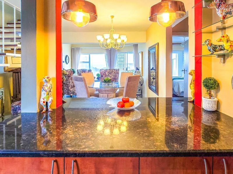 Open-plan living area featuring a granite kitchen breakfast bar, pendant lighting, and an open-tread staircase leading to the upper level.