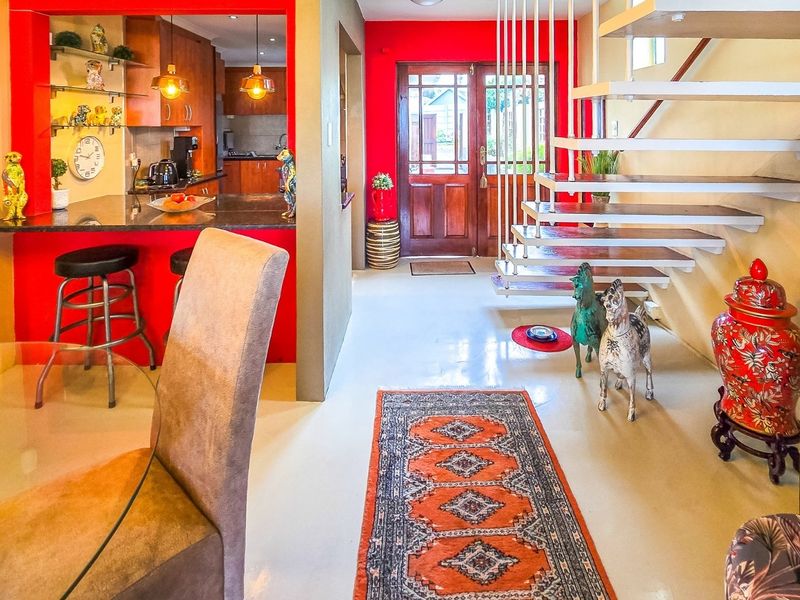 Open-plan living area featuring a modern floating staircase, polished concrete floors, and a breakfast bar connecting to the kitchen.