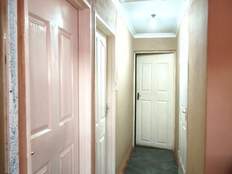 A functional hallway featuring tiled flooring, coved ceilings, and multiple interior doors providing access to various rooms within the home.