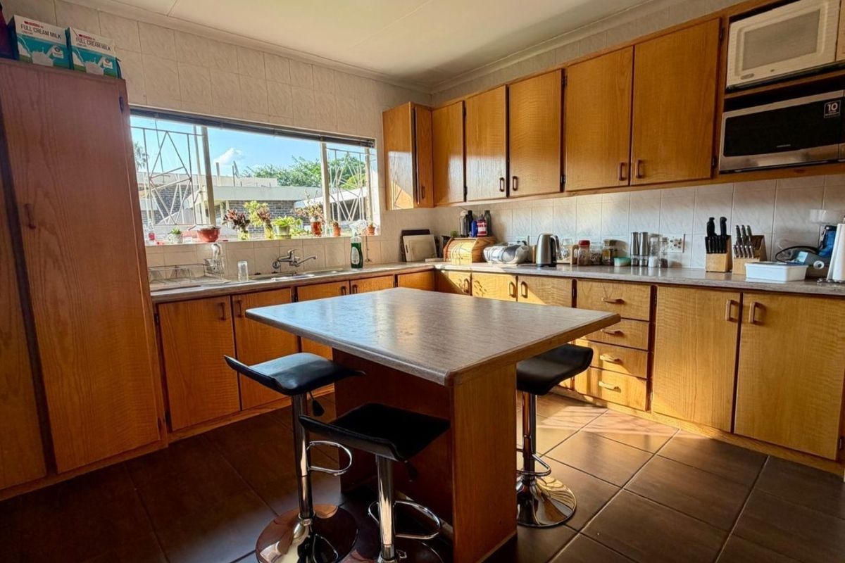A functional kitchen featuring wooden cabinetry, laminate countertops, a central island, and built-in appliances, offering a classic layout with ample storage space.