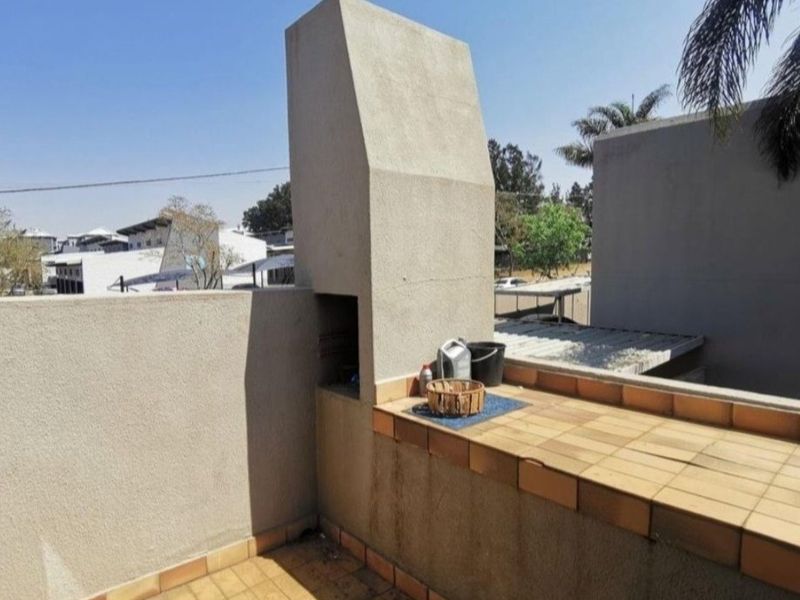 Outdoor balcony area featuring a built-in braai, tiled countertop, and tiled flooring, offering a functional space for outdoor cooking and entertainment.