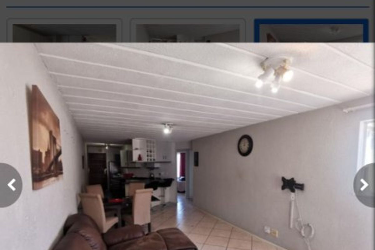 An open-plan living and kitchen area featuring tiled flooring and ceiling panels, providing a functional layout for daily living.