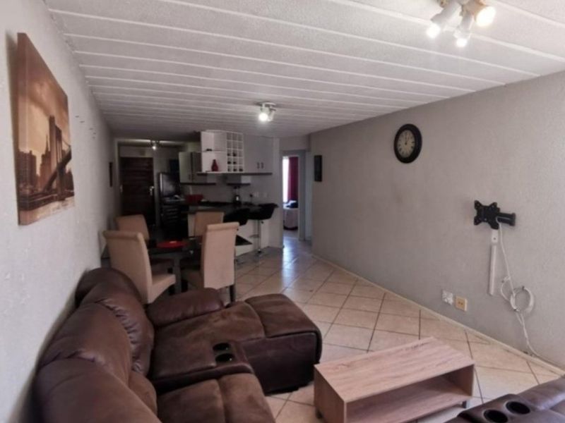Open plan living and dining area featuring tiled flooring and a functional kitchen space with built-in cabinetry and a breakfast bar.
