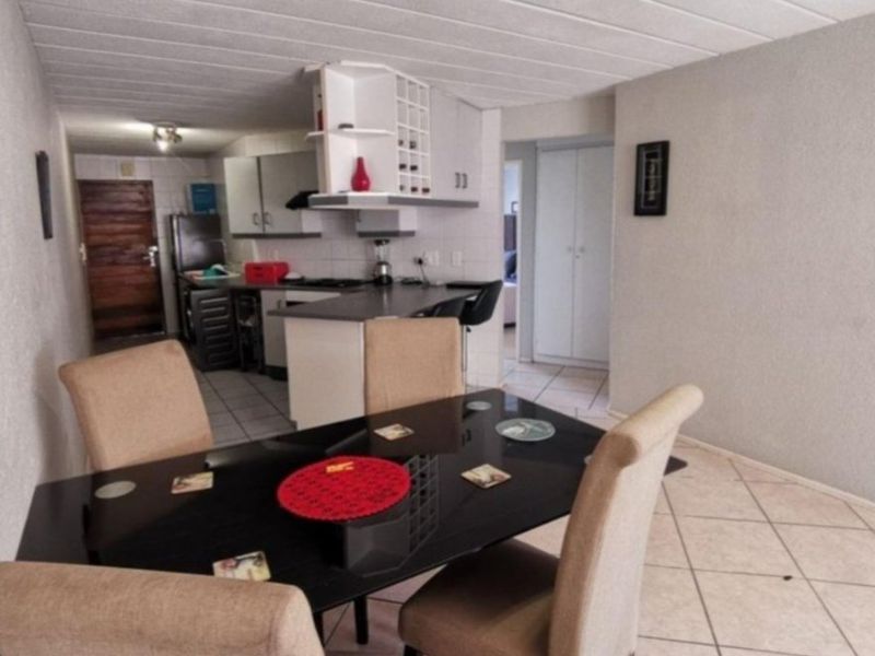 Open plan living and dining area featuring a functional kitchen with built-in cabinetry, island, and tiled flooring throughout.