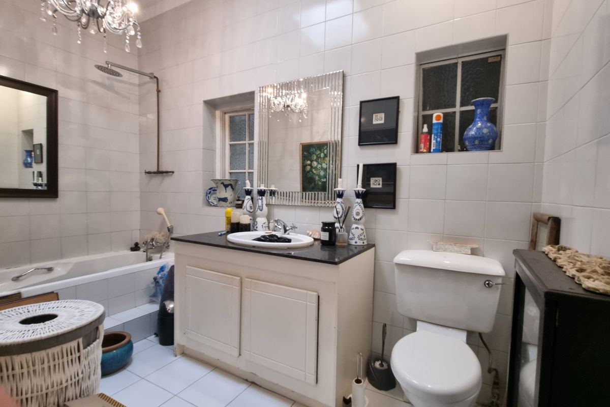 A functional bathroom featuring a built-in vanity with stone countertop, bathtub with wall-mounted shower, and tiled finishes throughout.