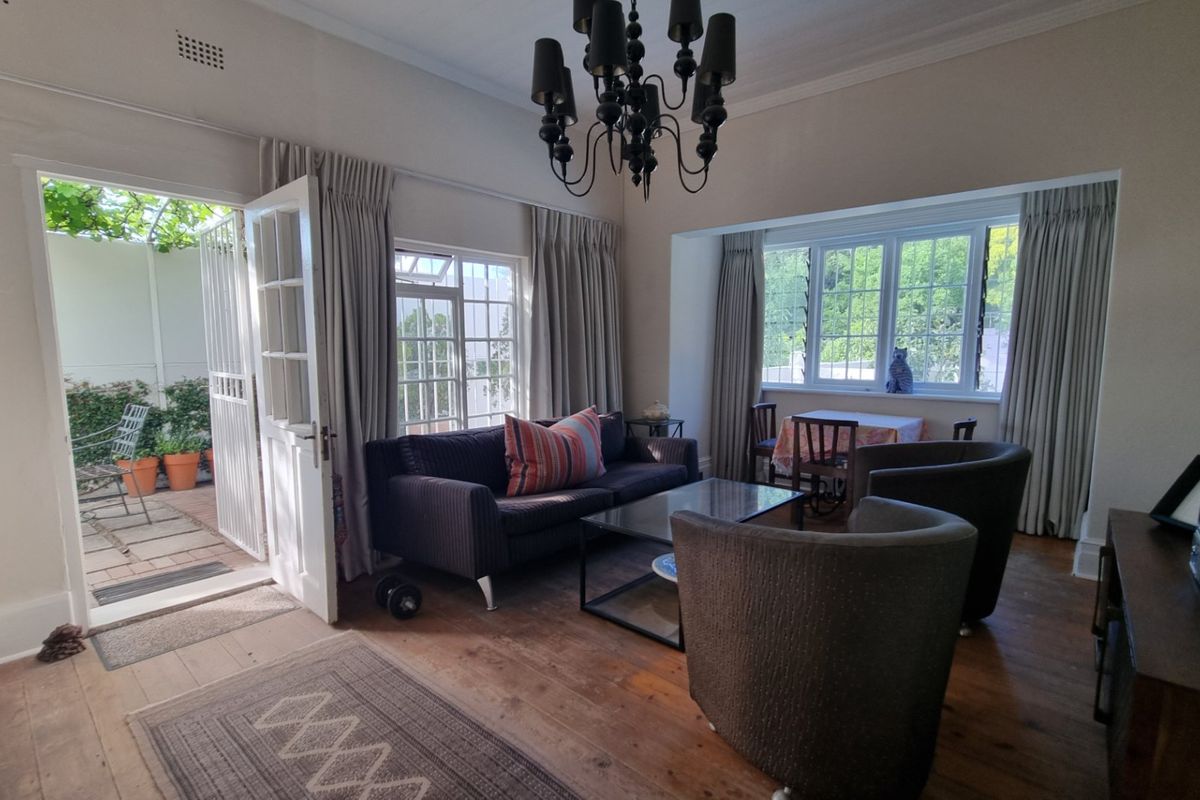 A bright living room featuring original hardwood flooring, classic cornicing, and direct access to an outdoor patio area through traditional french doors.