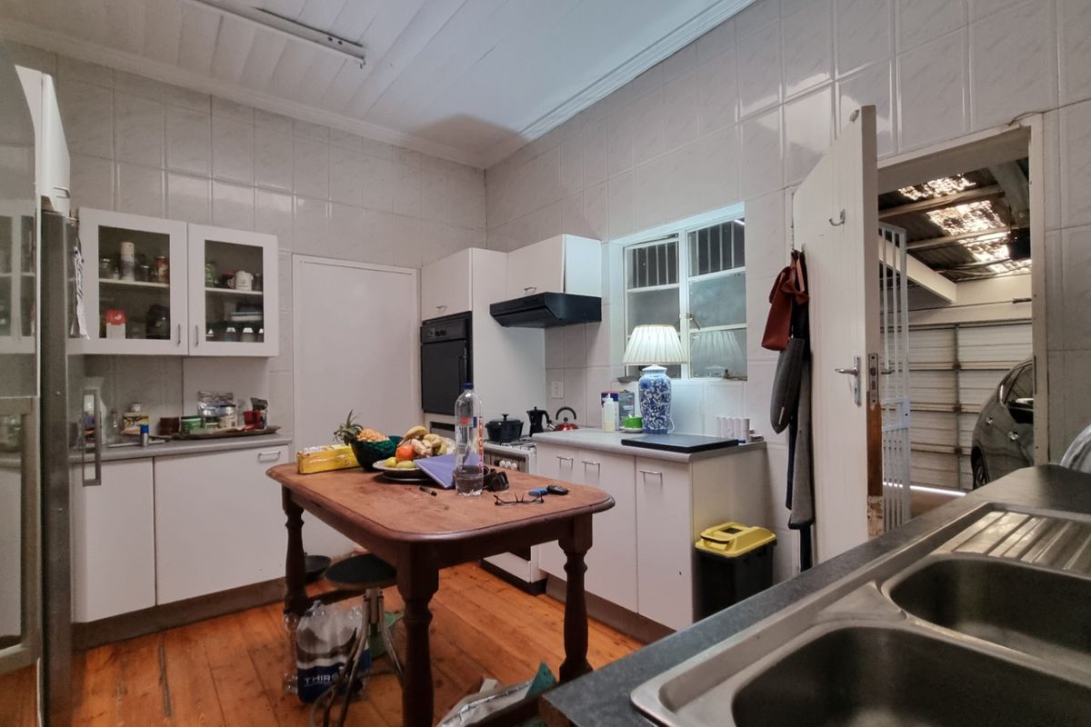 A functional kitchen featuring white cabinetry, built-in oven, extractor fan, and double sink, with tiled walls and timber flooring.