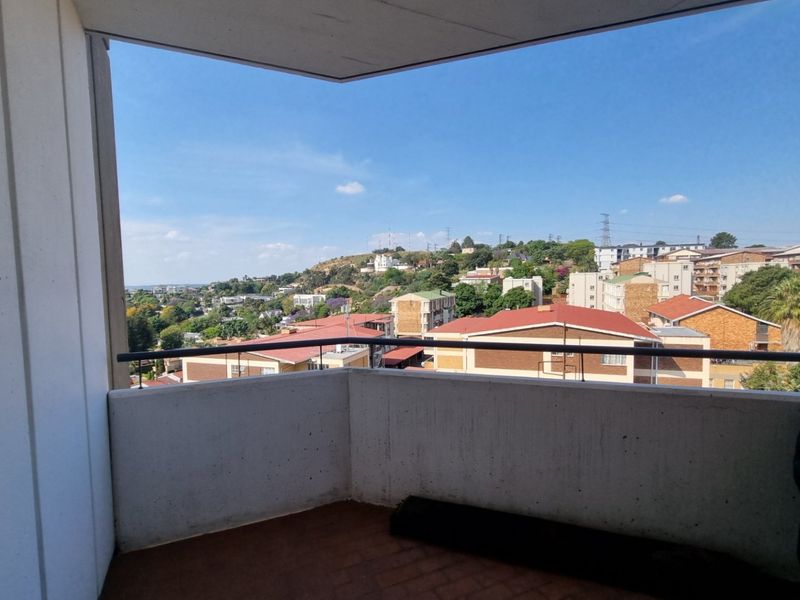 A balcony featuring a concrete balustrade with metal railing, offering an elevated view of the surrounding residential neighborhood.