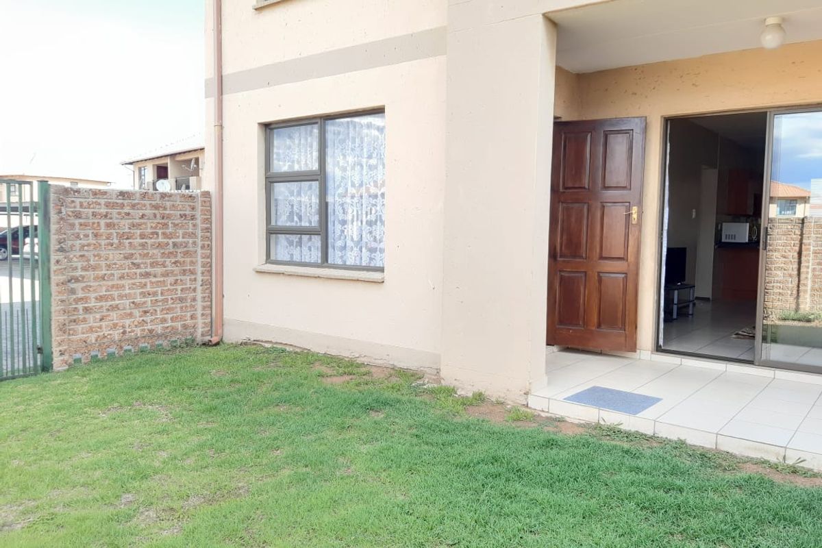Rear view of the apartment featuring a small private garden, a tiled patio area, and direct access through a sliding glass door.