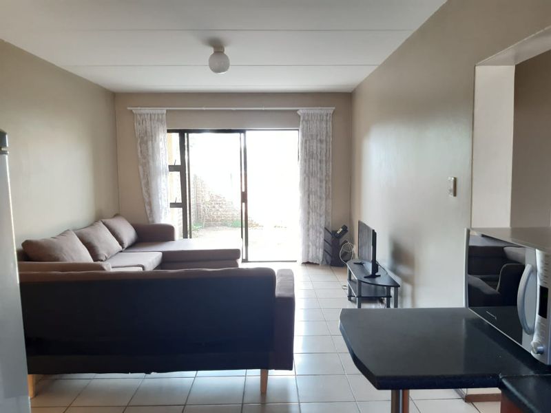 Open-plan living area featuring tiled flooring and a sliding glass door leading to an outdoor space, with an adjacent kitchen breakfast counter.