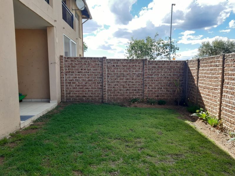 A private rear garden featuring a small lawn area, a tiled patio, and enclosed by brick boundary walls.