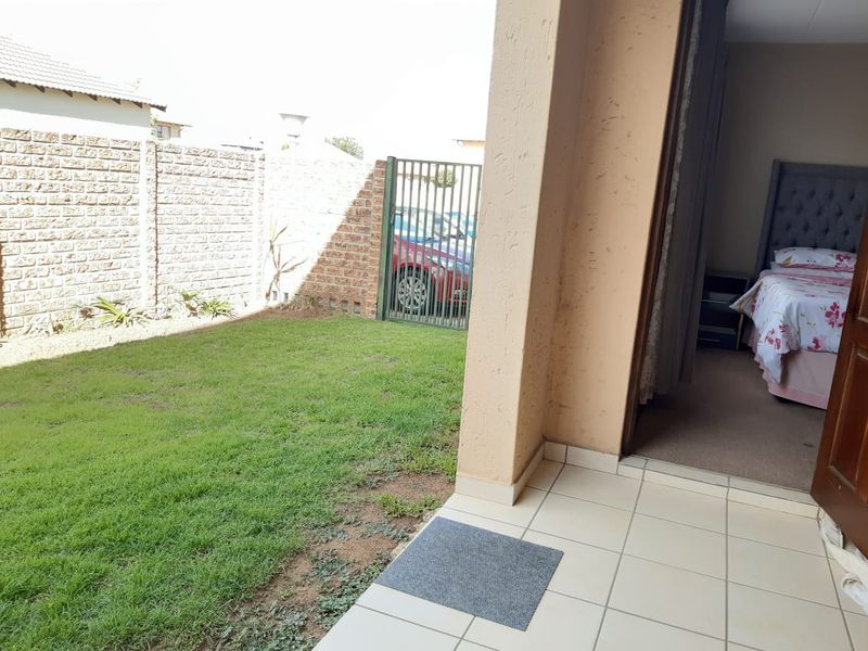 A private patio area with tiled flooring, leading directly from the bedroom to a small enclosed garden with a brick boundary wall.