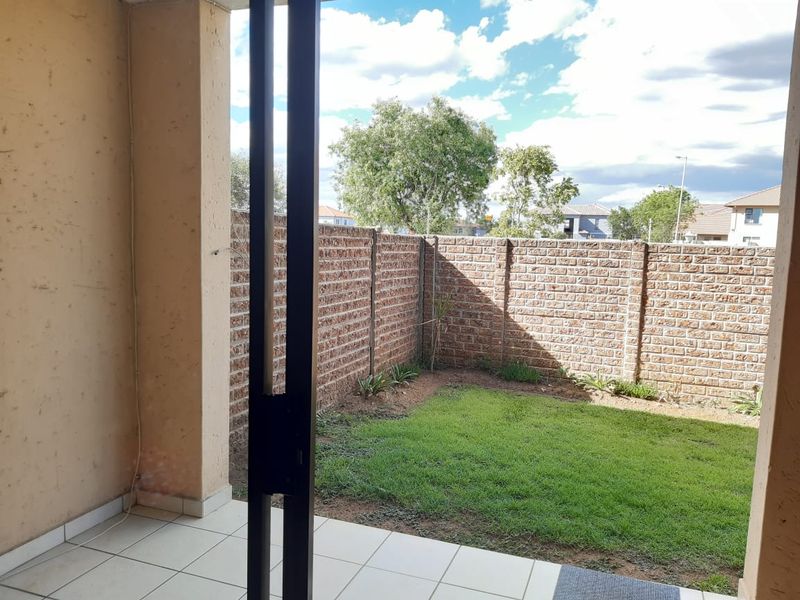 A covered patio area featuring tiled flooring, leading out to a private garden enclosed by a brick boundary wall.