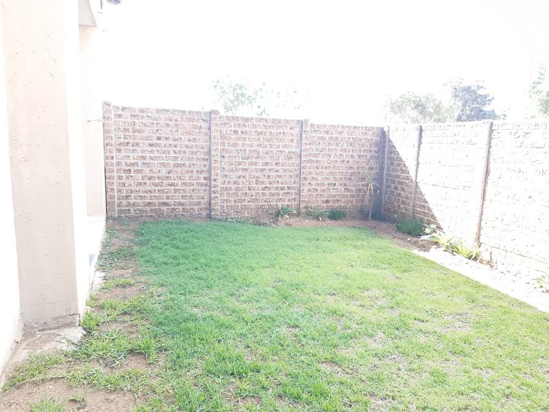 A private rear garden area featuring a lawn enclosed by precast concrete boundary walls.