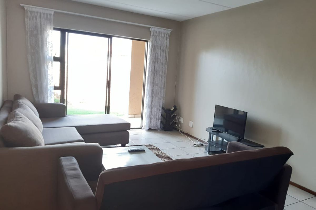 A living room featuring tiled flooring and a sliding glass door providing access to an outdoor area.