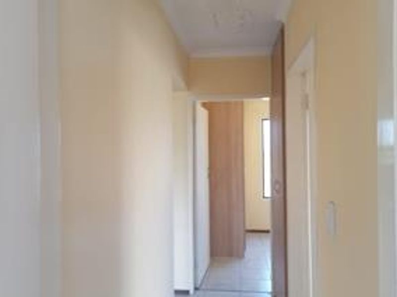 A functional hallway featuring tiled flooring and built-in storage cupboards, providing access to adjacent rooms within the apartment.
