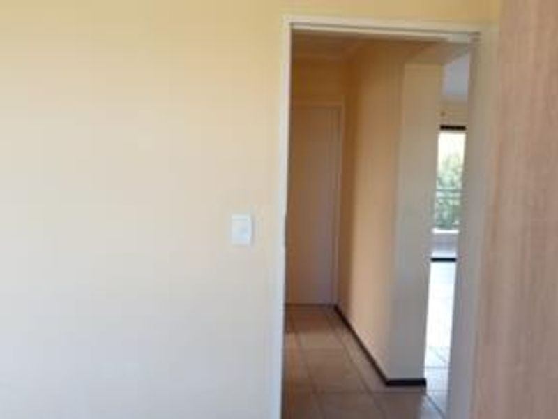 A view through an interior hallway with tiled flooring, connecting to other living spaces within the apartment.