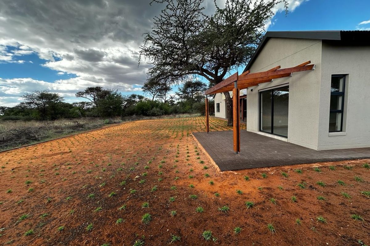Rear view of the property featuring a paved patio with a timber pergola, sliding glass doors, and a newly landscaped garden area.