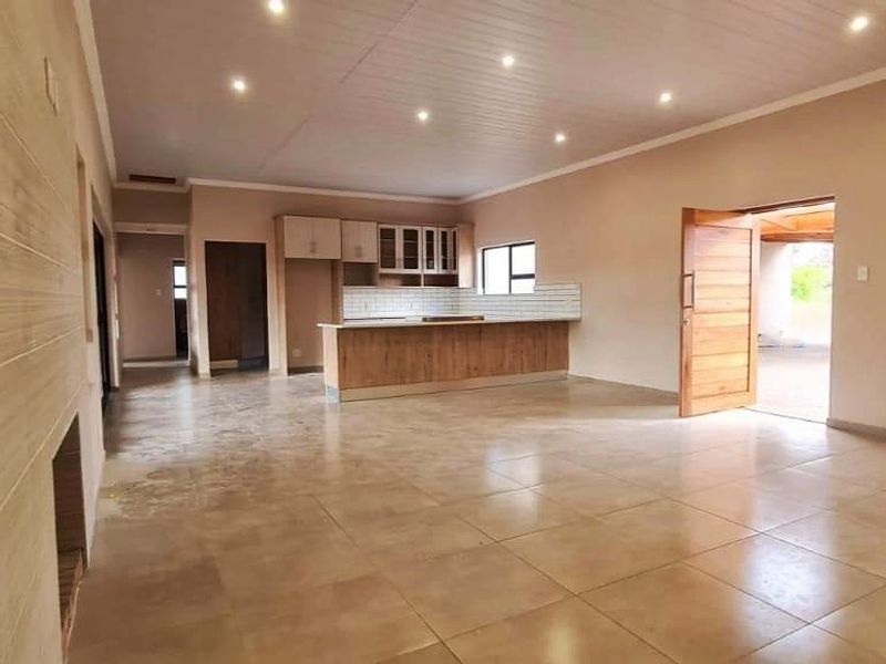 Spacious open-plan living and kitchen area featuring tiled flooring, recessed lighting, and a central kitchen island with built-in cabinetry.